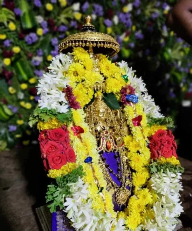 Adorned golden Utsava Murti deity with flower garlands during temple festival